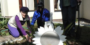 Anita Botha, wie se gesondheid intussen redelik herstel het, plant hier saam met Thando, HaS se regterhand tuinier  